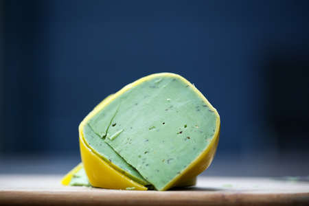 Dutch pesto cheese slices on a wooden background in a closeup view.の写真素材