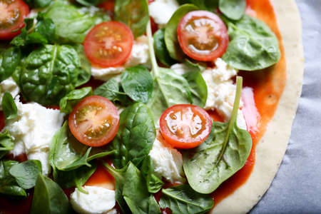 Traditional home made thin crust pizza with spinach, tomato, and mozzarella