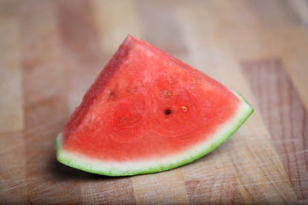 Fresh slices of red watermelon on a wooden surface in a closeup view. Selective focus.