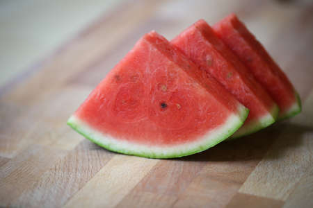 Fresh slices of red watermelon on a wooden surface in a closeup view. Selective focus.の写真素材