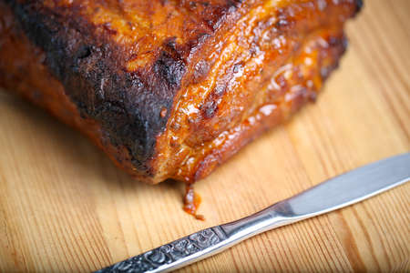 Piece of roasted pork on a wooden board in a closeup view