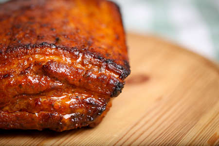 Piece of roasted pork on a wooden board in a closeup viewの写真素材