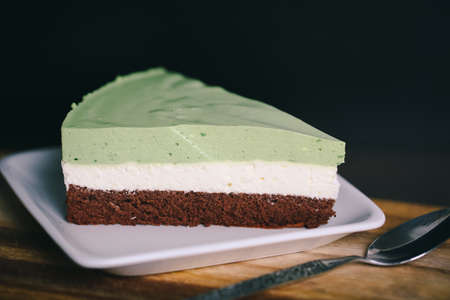 A piece of matcha/green tea, coconut powder, and chocolate cake in a closeup view.の写真素材