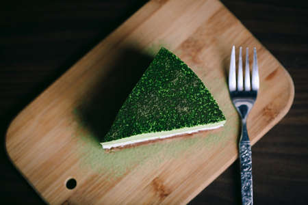 A piece of matcha/green tea, coconut powder, and chocolate cake in a closeup view.の写真素材