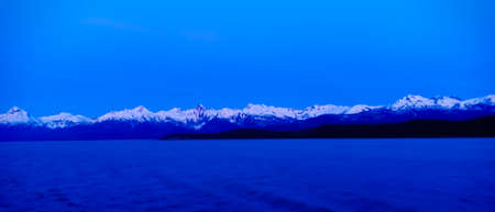 Snow covered mountain and blue oceanの写真素材