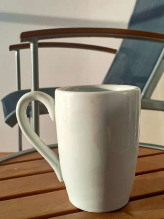 coffee cup on a table near to a chairの写真素材