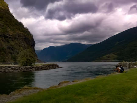 view of lake and mountains under cloudy sky near flam cruise port norwayの写真素材