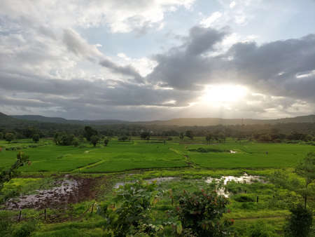beautiful river near mountain under cloudy sky and a rice fieldの写真素材