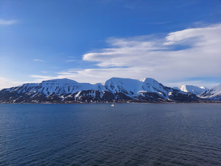 Architectural beauty against mountainous coastline with nautical vessel sailing on calm waters. a view from salbard longyearbyen norwayの写真素材