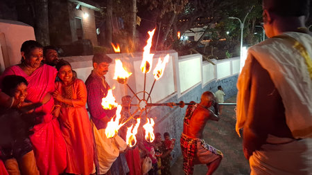 india kerala 3/7/2025 A lively traditional festival scene showcasing a unique fire performance and joyful participants lighting up the night with cultural significance and shared festivities.の写真素材