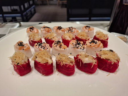 A beautifully arranged selection of sushi featuring unique toppings and colorful presentations served elegantly on a white plate.の写真素材