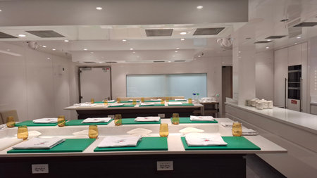Bright and contemporary culinary classroom equipped with individual workstations showcasing a sleek and organized setup for teaching and learning cooking skills in a professional kitchen environment.の写真素材