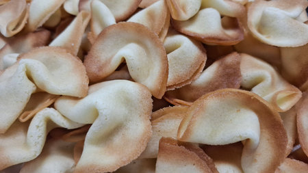 A detailed view of crisp, golden-brown fortune cookies stacked together, showcasing their texture and classic shape, evoking thoughts of desserts, cultural cuisine, and a sense of agreeable curiosity.の写真素材