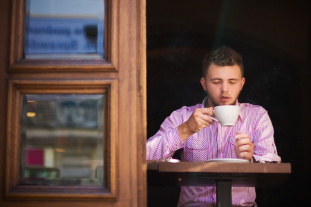 Portrait of a young man drinking coffee and smoking の写真素材