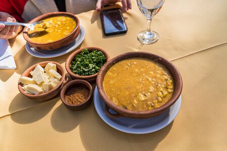 Locro, typical Argentine food, accompanied by bread and a glass of wine, with spoons.の写真素材
