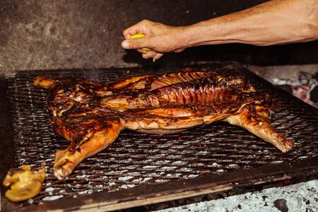 Traditional suckling pig cooked on the charcoal grill. The little pig is roasted whole on an open...