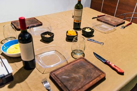 Family house table prepared to celebrate the gathering of friends, with sauces, cheese, wine and dishes.の写真素材