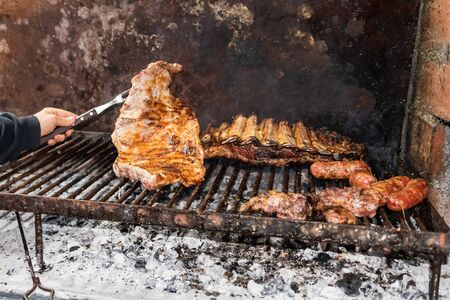 "Parrillada" Argentine barbecue make on live coal (no flame), beef "asado", bread, "Chorizo" and Grilled beef ribs with a hot rack, close up, focus selectの写真素材