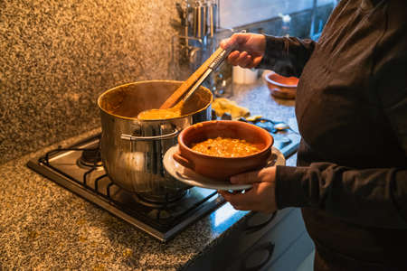 woman serving locro, typical Argentine food on handmade ceramic plates.