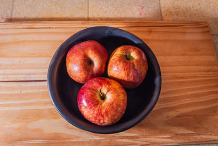 Close-up of several ripe rich, fresh, organic, juicy green apples in a black ceramic bowl on a wooden table. Copy space.Selective focus.の写真素材