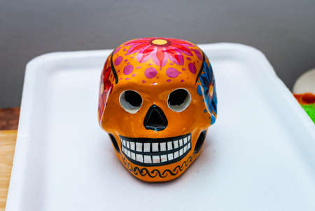 Orange Painted human skull with flowers for Mexico's Day of the Dead on color background, selected focus.の写真素材