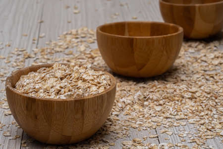 Oats with a wooden cup on white wood background