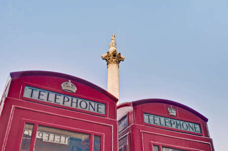 Nelsons Column on Trafalgar Square behing red telephones at London, Englandの写真素材