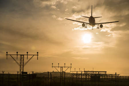 Silhouette of an airplane landing at dusk.