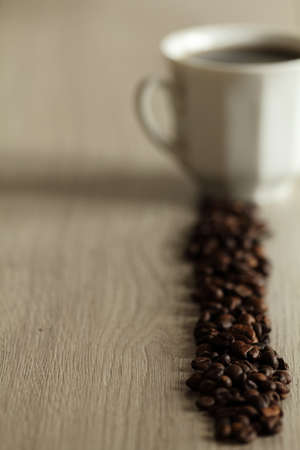 coffee beans with white cup of coffee on wooden tableの写真素材
