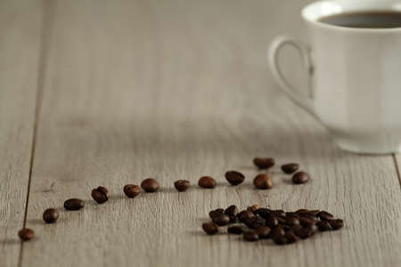 white cup of coffee on wooden table with coffee beansの写真素材
