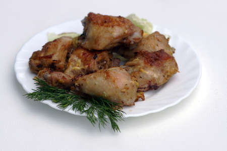 Pieces of fried chicken on a white plate,decorated with greens of a parsley 