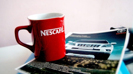 Red mug stands on a color magazine.のeditorial素材