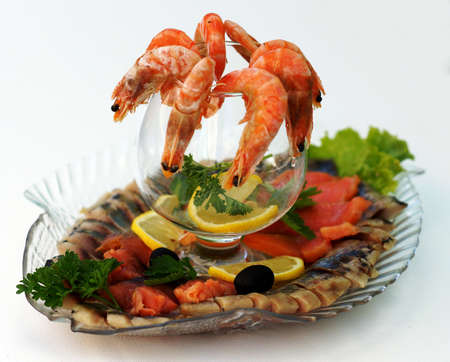Boiled shrimps with lemon and parsley on a platter with an assortment of fish dishes.                               の写真素材