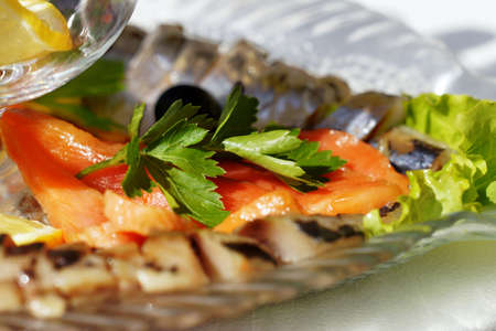 Trout cut slices and decorated with parsley on a platter with an assortment of fish dishes.の写真素材