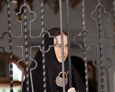 5 July 2013 ,the city Krasnousolsk , Bashkortostan,Russia   The feast of the Tabynsk icon of the Mother of God - the main Shrine of the believers of the southern Urals and Orenburg regions, The young novice closes wrought iron gates のeditorial素材
