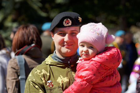 may 2013, Beloretsk, Bashkortostan, Russia Happy young man in camouflage uniform with a child in her arms.のeditorial素材