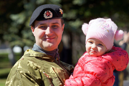 may 2013, Beloretsk, Bashkortostan, Russia Happy young man in camouflage uniform with a child in her arms.のeditorial素材