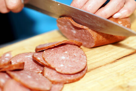 A woman cuts the knife sausage for Breakfast .の写真素材