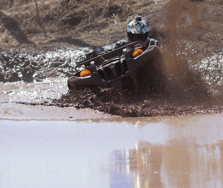 Extreme driving ATV on overcoming mud obstacles.