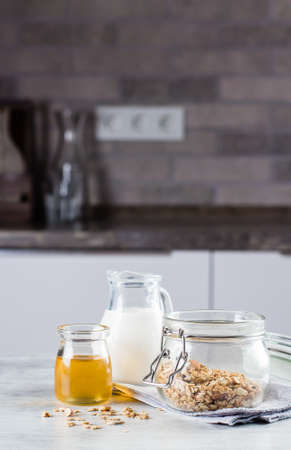 Breakfast food concept. Homemade granola, milk or yogurt and honey on table background on the kitchen. Copyspace for textの写真素材