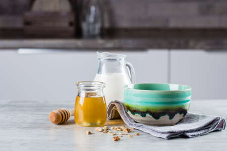 Breakfast food concept. Homemade granola, milk or yogurt and honey on table background on the kitchen. Copyspace for textの写真素材