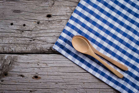 Blue checkered tablecloth and spoon on wooden rustic table background. Copy space, top viewの写真素材