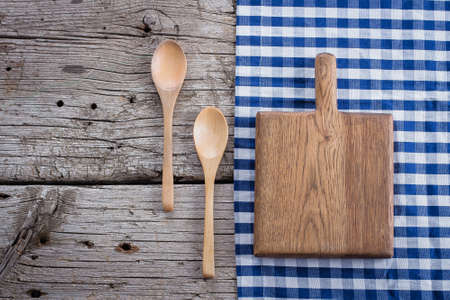 Blue checkered tablecloth and wooden cutting boardon wooden rustic table background. Copy space, top viewの写真素材