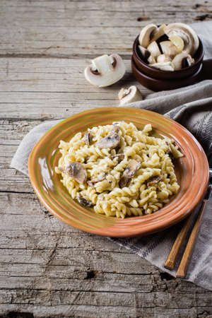 Italian pasta fusili with mushrooms and cream sauce on wooden table, copy space, top view. Autumn Food Conceptの写真素材