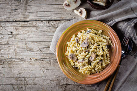 Italian pasta fusili with mushrooms and cream sauce on wooden table, copy space, top view. Autumn Food Conceptの写真素材