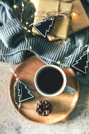 Cozy winter composition with a cup of coffee, present box, gifts, sweater and garland lights. Christmas or New Year 2020 holiday concept. Cozy, mood, lifestile, still lifeの写真素材