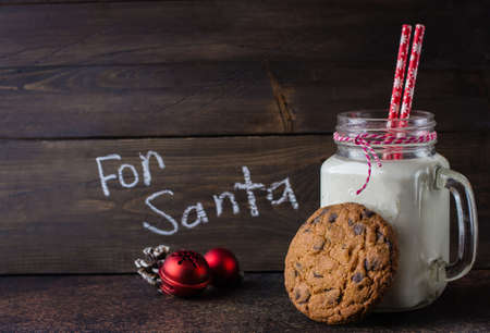 Chocolate chip cookies with a glass of milk on dark stone concrete table background. Christmas Holiday decoration. Copy Space.の写真素材