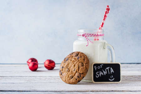 Chocolate chip cookies with a glass of milk on white wooden table background. Christmas Holiday decoration. Copy Space.の写真素材