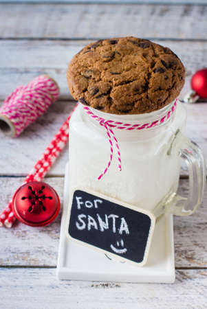 Chocolate chip cookies with a glass of milk on white wooden table background. Christmas Holiday decoration. Copy Space.の写真素材