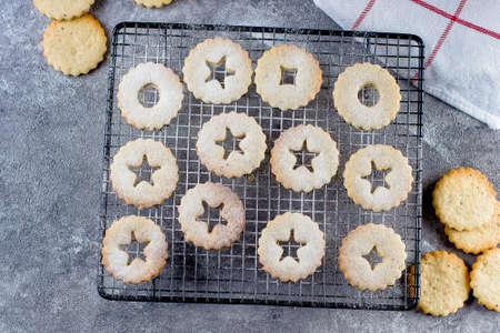 Holiday Sweet Food. Process making of cookies. Christmas Linzer cookies with red berry jam on gray concrete table background. Top view, flat layの写真素材